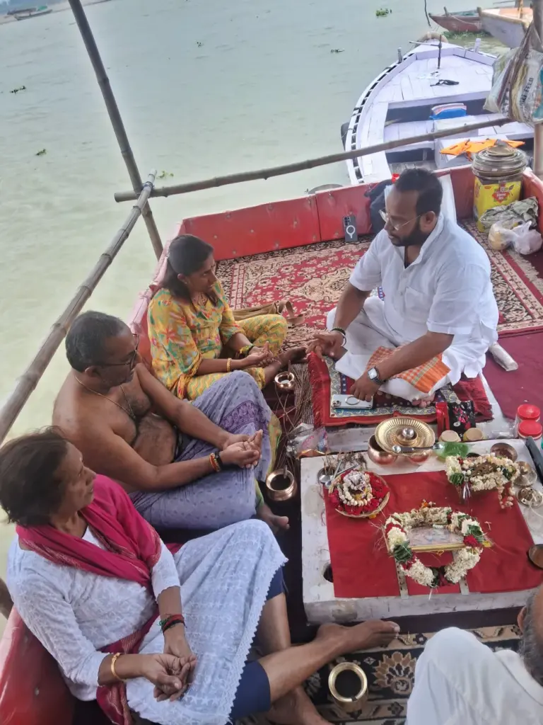 Family and priest seated on a boat by the river in Varanasi.