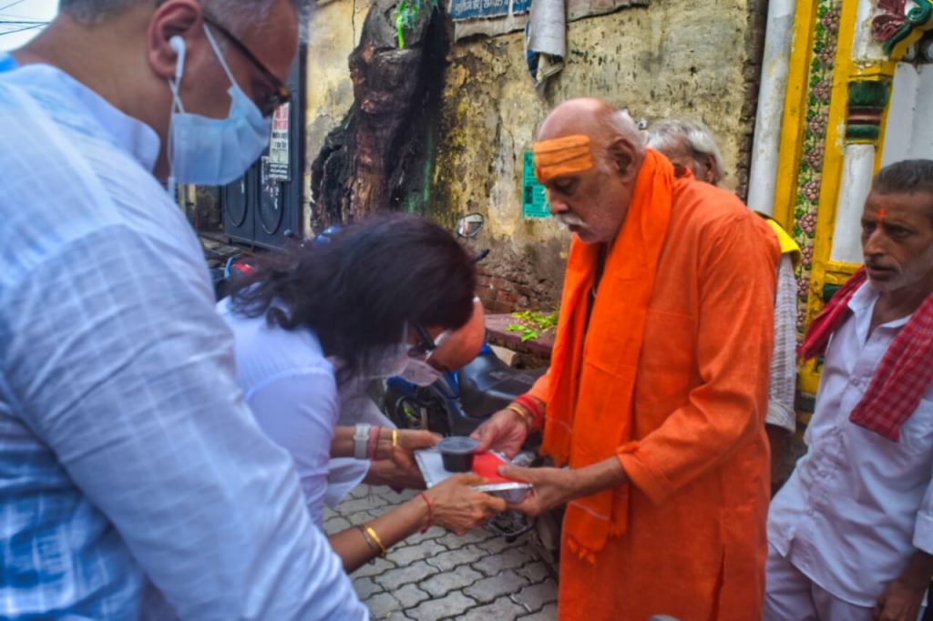 A lady donating food material to a priest