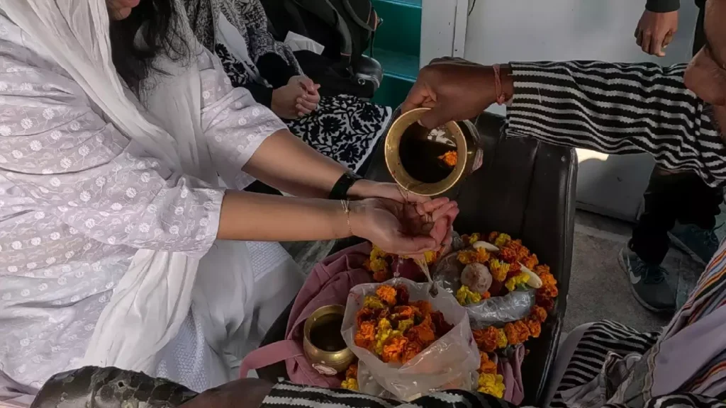 A feamle devotee performing asthi visarjan in prayagraj-What services are included in the Asthi Visarjan package in Prayagraj