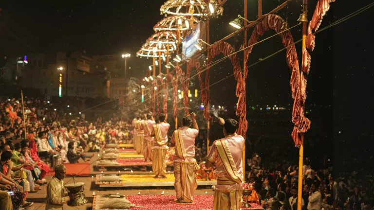 Night ritual with priests, elaborate decorations, and a large crowd by the water- Daily Ritual Practices at the Ghats