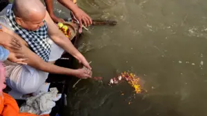 A family performs ancestral rites from a boat, releasing sacred flower offerings into the Sangam- Asthi Visarjan Package cost from Malaysia