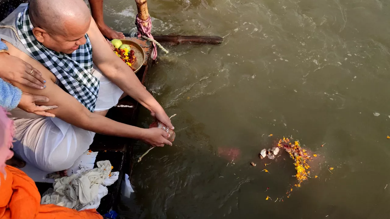 A family performs ancestral rites from a boat, releasing sacred flower offerings into the holy sangam- NRI shradh puja Prayagraj
